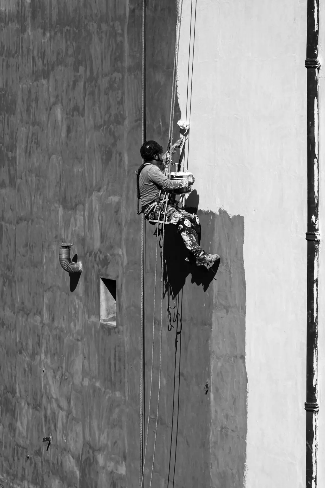 Profissional suspenso por cordas trabalhando na fachada de um edifício