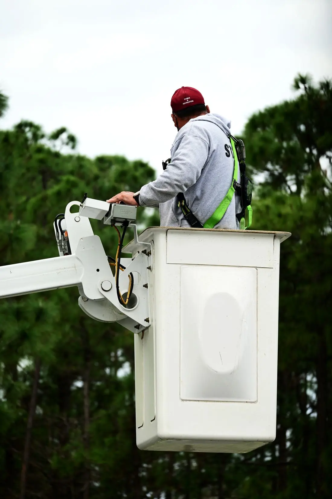 Trabalhador com cinto de segurança em cesto de caminhão com plataforma elevatória