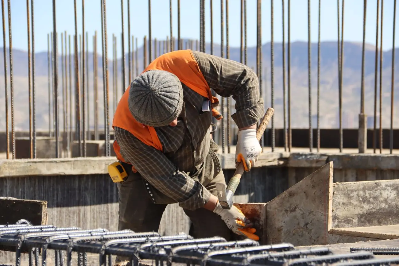 Trabalhador montando armação de aço em estrutura de concreto